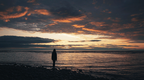 Woman staring out at the beautiful sunset on a beach